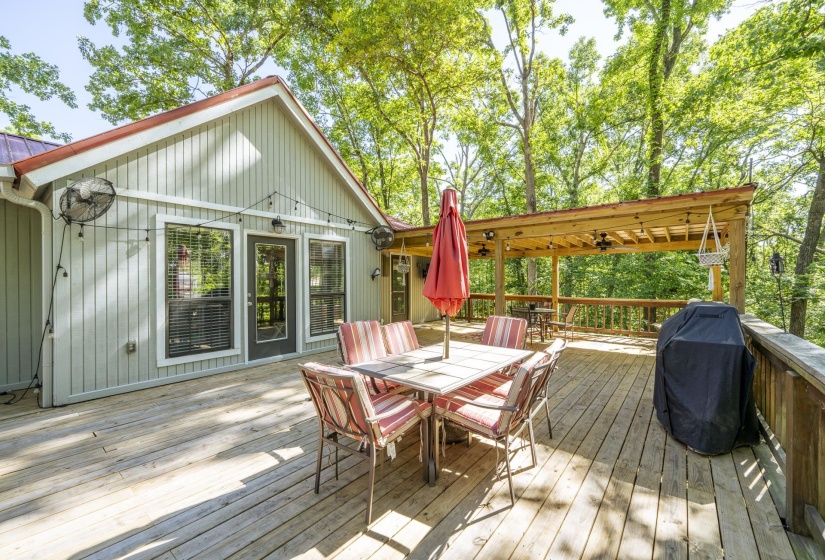 Expansive wood deck with a partial covered pergola, offering multiple access points to the residence
