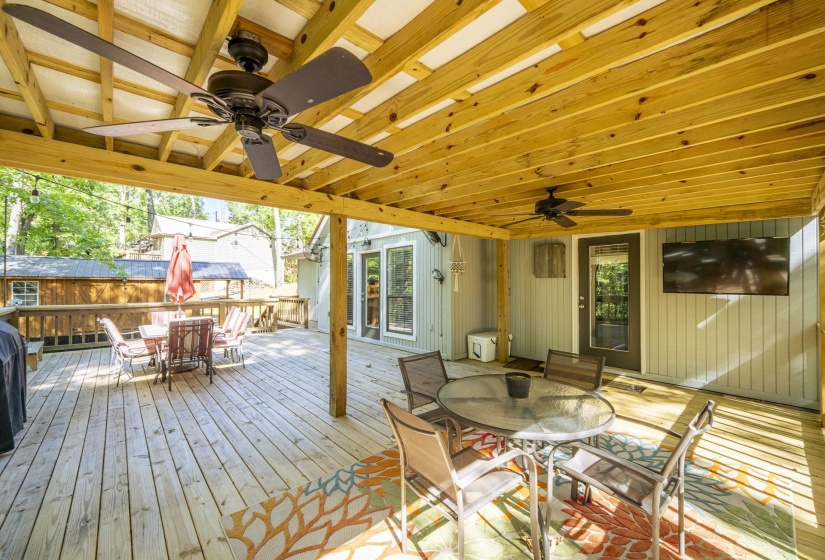 Expansive outdoor deck featuring wood-finish flooring and a covered portion with exposed wood beams