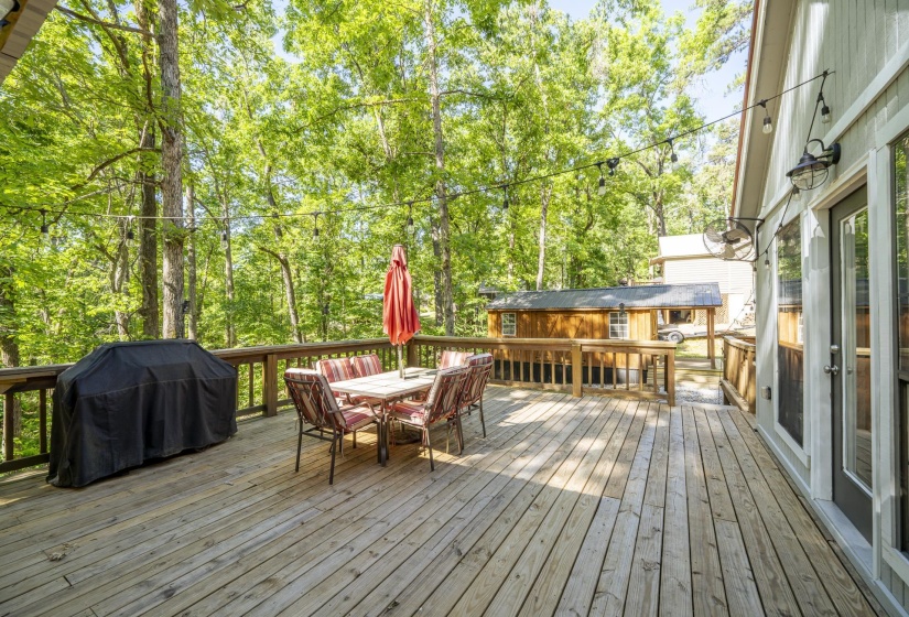 Spacious wood deck featuring a protective railing and string lighting