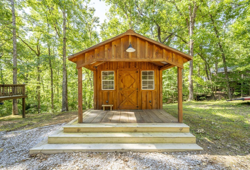 Wood-sided outbuilding featuring a covered porch, two windows, and a single door