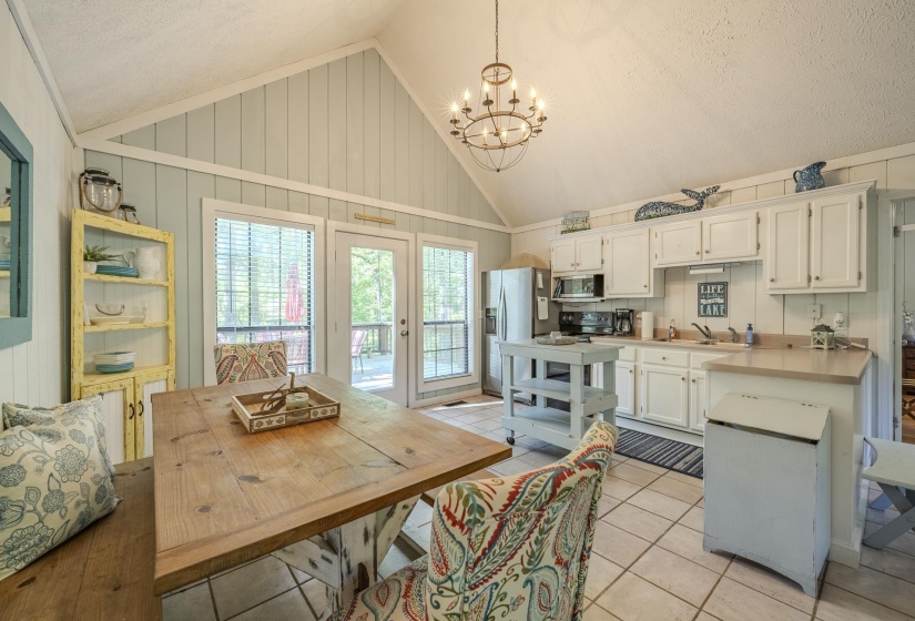 Open-concept kitchen and dining area featuring a vaulted ceiling with a chandelier