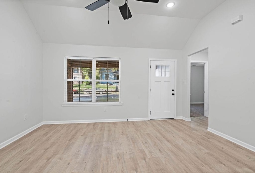 Unfurnished living room featuring lofted ceiling, light wood-style flooring, and a ceiling fan