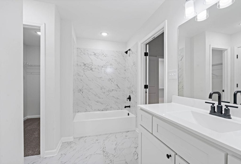 Full bathroom featuring a spacious closet, shower / bathtub combination, vanity, and light marble finish floors