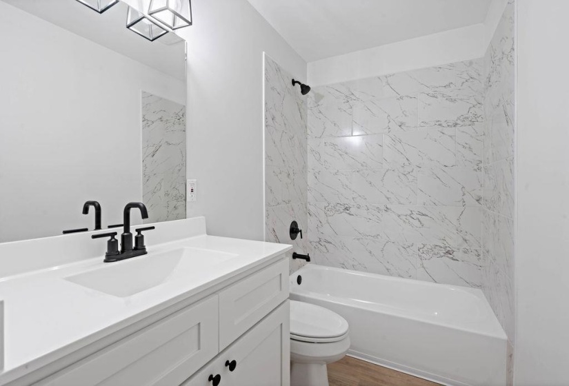 Bathroom with shower / washtub combination, vanity, and wood finished floors