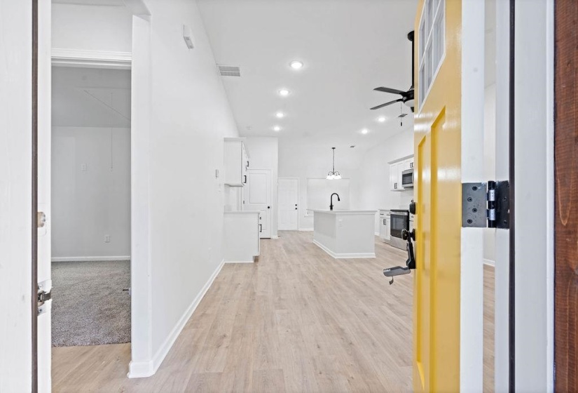 Hallway featuring light wood-style floors, recessed lighting, and lofted ceiling