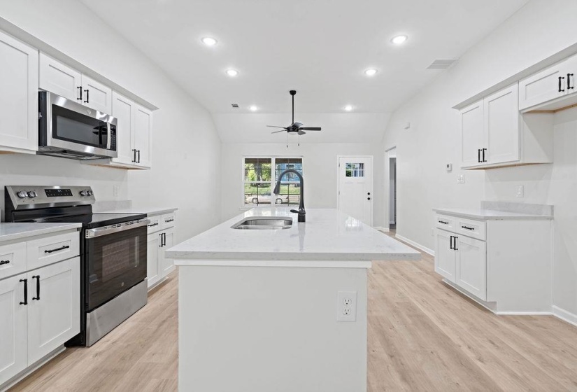 Kitchen featuring appliances with stainless steel finishes, white cabinets, lofted ceiling, recessed lighting, and light wood finished floors