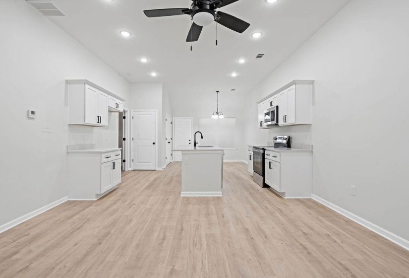 Kitchen featuring stainless steel appliances, white cabinets, recessed lighting, light wood-style flooring, and pendant lighting