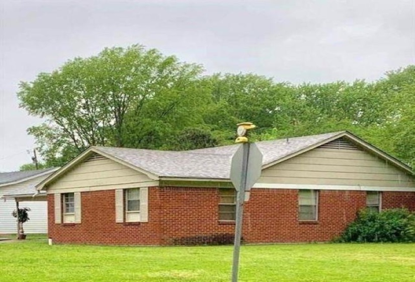 View of side of property with brick siding and a yard