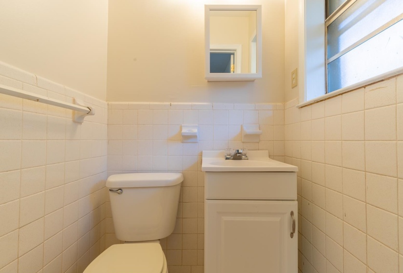 Bathroom featuring tile walls, vanity, toilet, and wainscoting