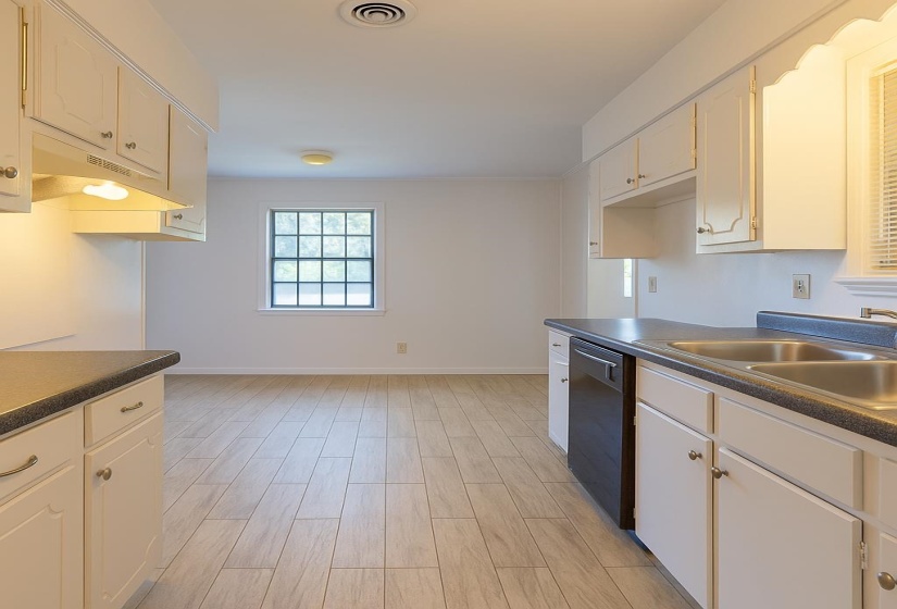 Kitchen with dishwasher, dark countertops, baseboards, and a sink