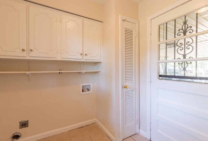 Laundry room with electric dryer hookup, washer hookup, cabinet space, light tile patterned floors, and baseboards