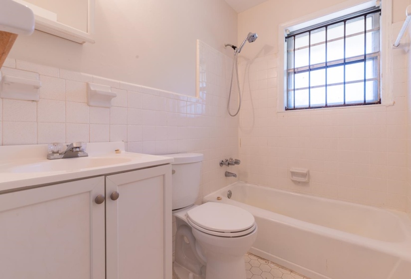 Full bath with toilet,  shower combination, vanity, tile walls, and tile patterned floors