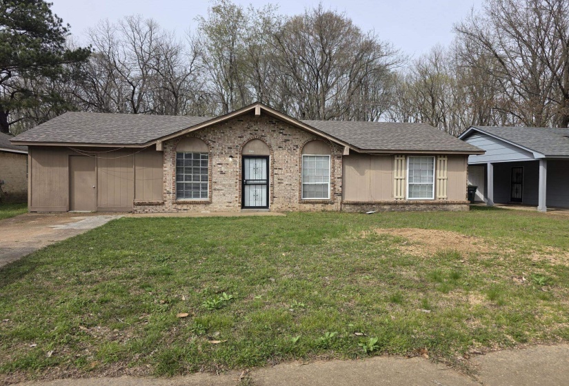 Ranch-style house with a shingled roof, a front lawn, and brick siding