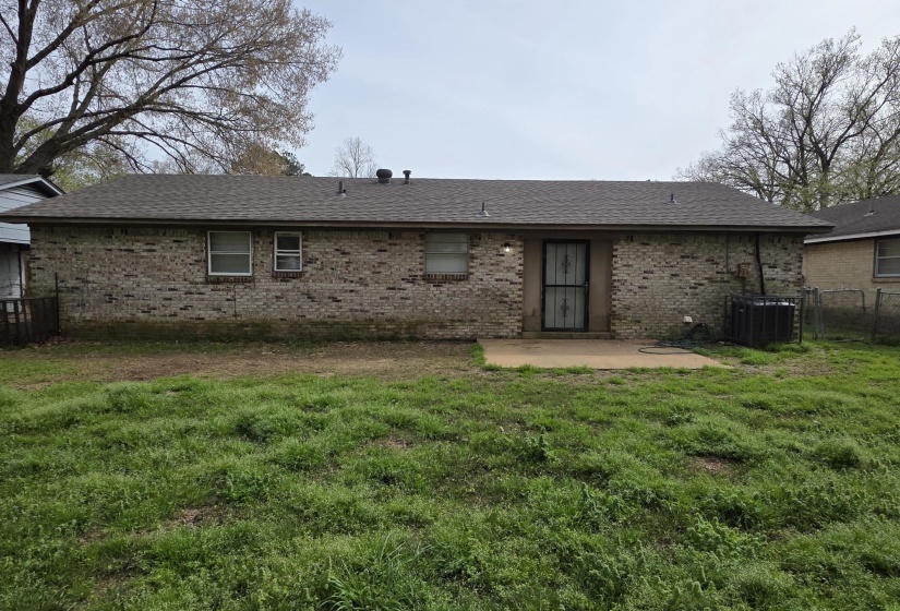 Rear view of property with a patio, brick siding, and roof with shingles