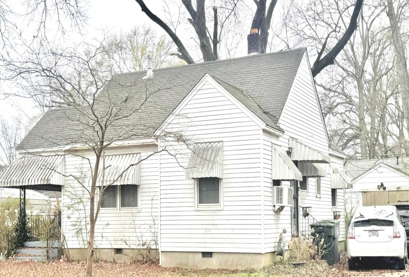 View of side of home with crawl space, a shingled roof, and a chimney