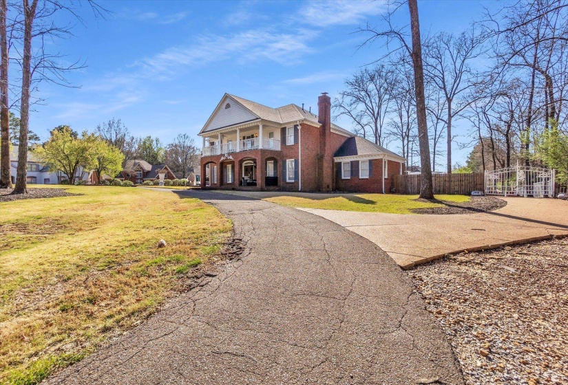 Neoclassical / greek revival house with brick siding, a chimney, covered porch, and driveway