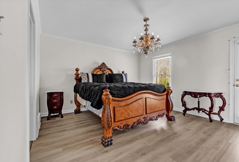 Bedroom with light wood-style flooring, ornamental molding, and a chandelier