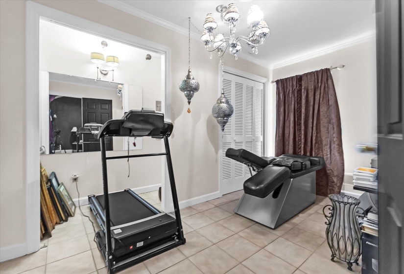 Workout room with crown molding, light tile patterned floors, and hanging lights