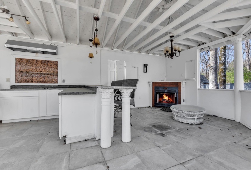 Kitchen featuring a kitchen breakfast bar, white cabinetry, hanging lights, a lit fireplace, and open floor plan