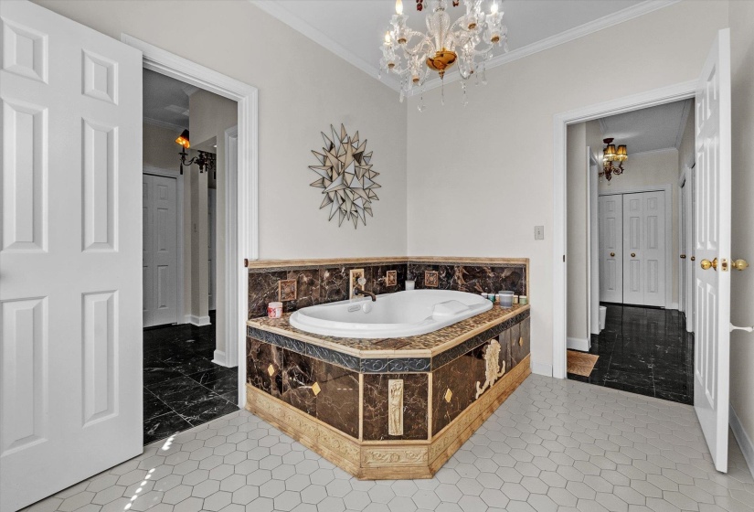 Bathroom with ornamental molding, a garden tub, and a chandelier