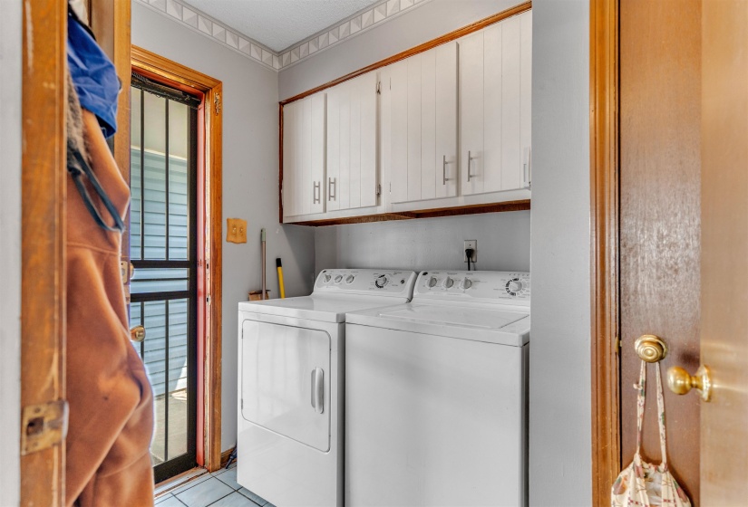 Laundry area with cabinet space, washing machine and dryer, and light tile patterned flooring