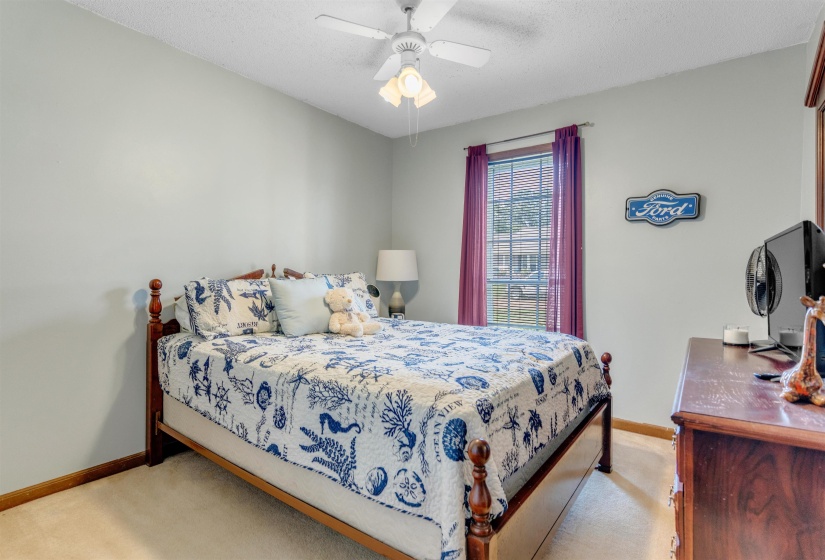 Bedroom with light colored carpet, a ceiling fan, and a textured ceiling