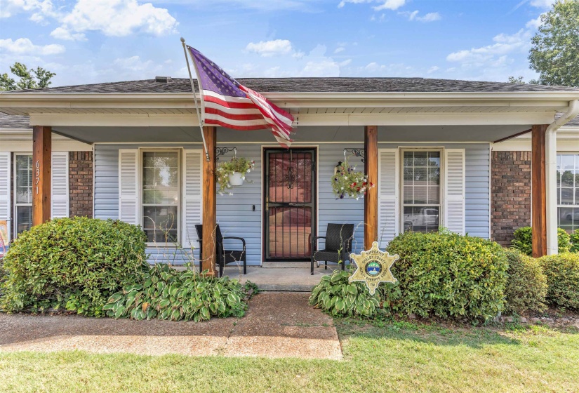 Entrance to property featuring a porch, a shingled roof, and brick siding