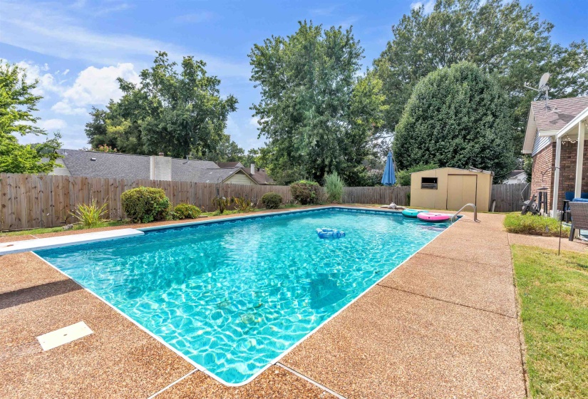View of pool featuring a fenced backyard, a storage unit, and patio surround