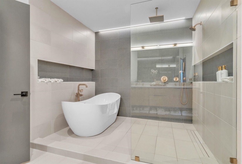 Bathroom featuring a soaking tub, a walk in shower, tile walls, light tile patterned floors, and double vanity