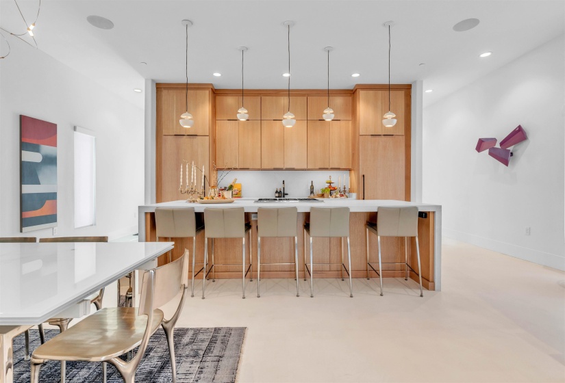 Kitchen with a breakfast bar, a large island, modern cabinets, finished concrete floors, and light stone countertops