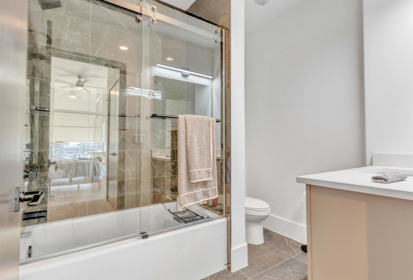 Full bathroom featuring vanity, enclosed tub / shower combo, and a ceiling fan