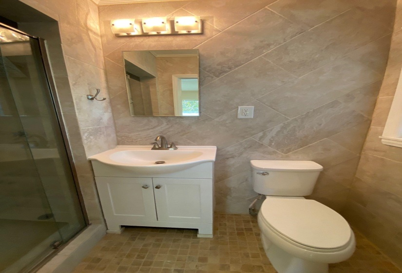 Full bath with vanity, a shower stall, tile walls, and light tile patterned floors