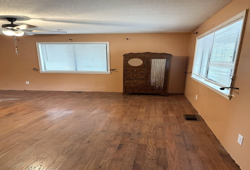 Unfurnished living room with wood finished floors, a textured ceiling, and a ceiling fan