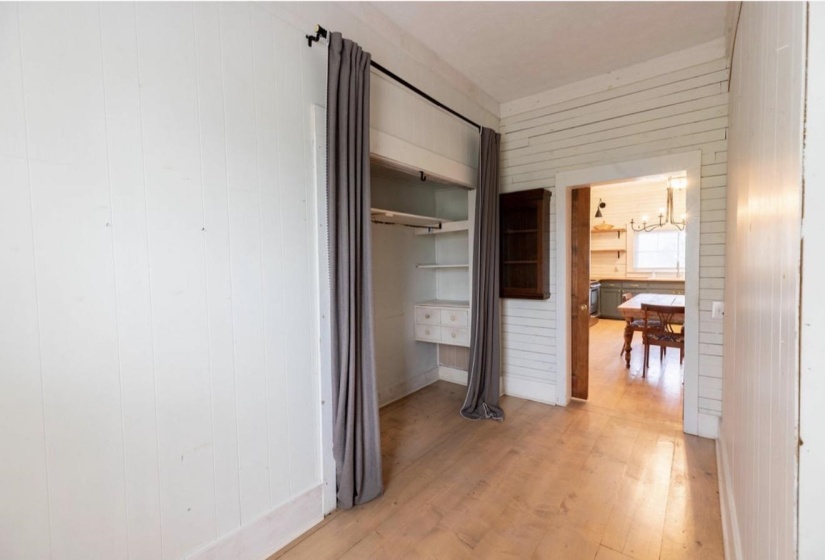 Hall with wooden walls, light wood finished floors, and hanging lights