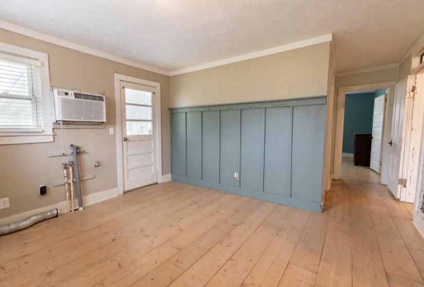 Unfurnished dining area with light wood-style floors, ornamental molding, a textured ceiling, and wainscoting