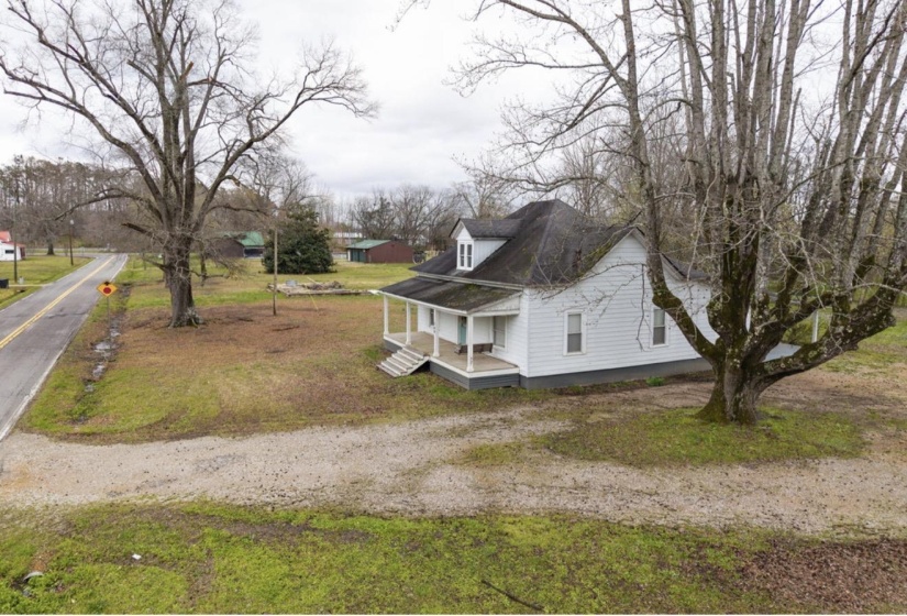 View of side of property with covered porch and a yard