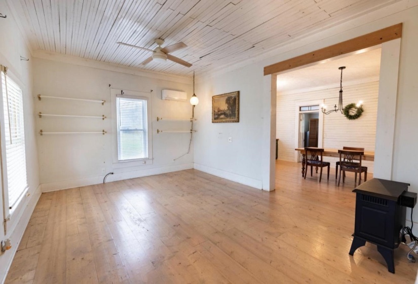 Living room with light wood-style floors, a ceiling fan, wooden ceiling, a wood stove, and hanging lights