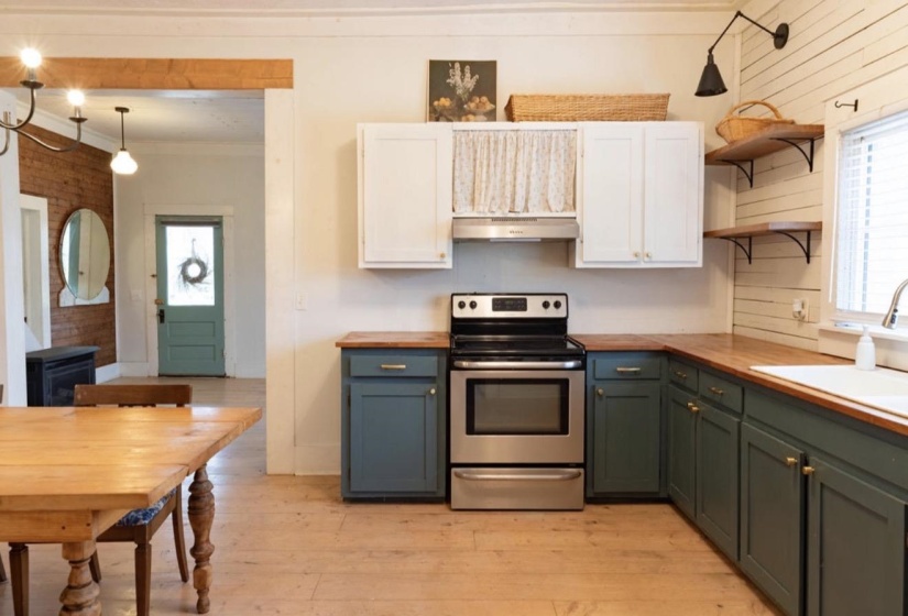 Dual tone kitchen with stainless steel electric range oven, wood counters, light wood-style floors, two tone cabinetry, and open shelves