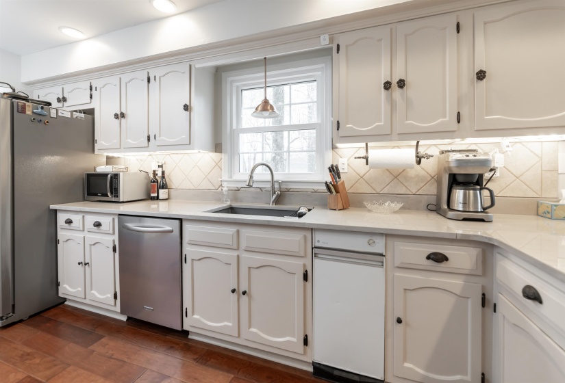 Kitchen featuring white cabinetry, stainless steel appliances, dark wood-style floors, light stone counters, and pendant lighting