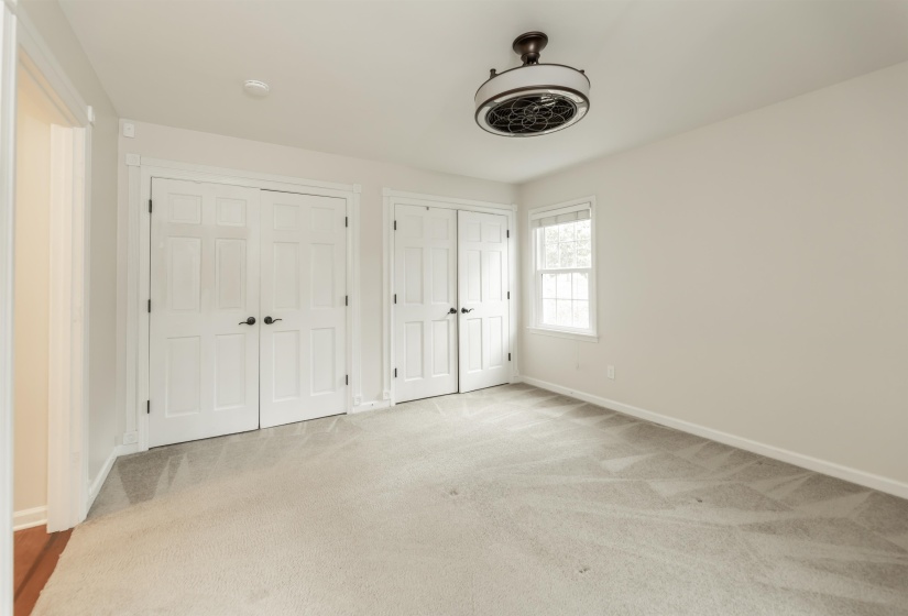 Unfurnished bedroom with multiple closets, light carpet, and ceiling fan