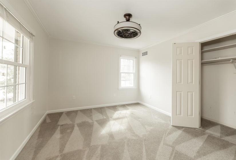 Unfurnished bedroom with ornamental molding, light carpet, and a closet