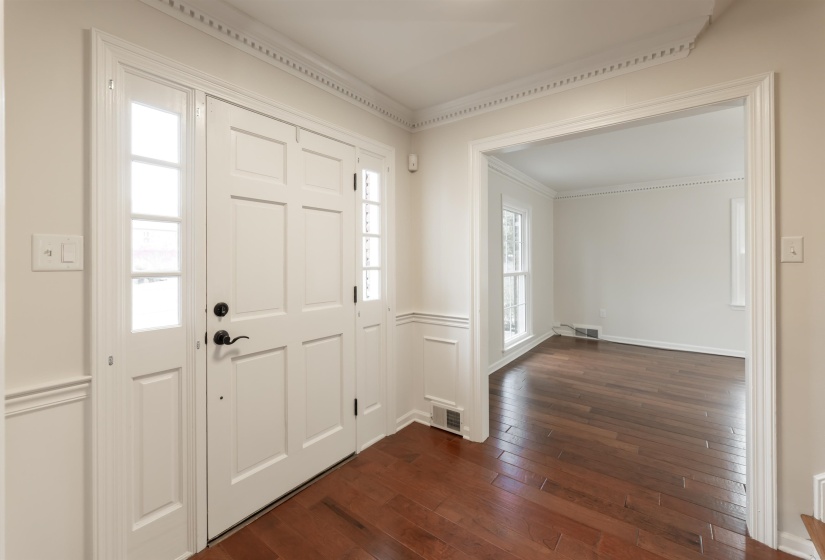 Entrance foyer featuring dark wood-style floors and ornamental molding