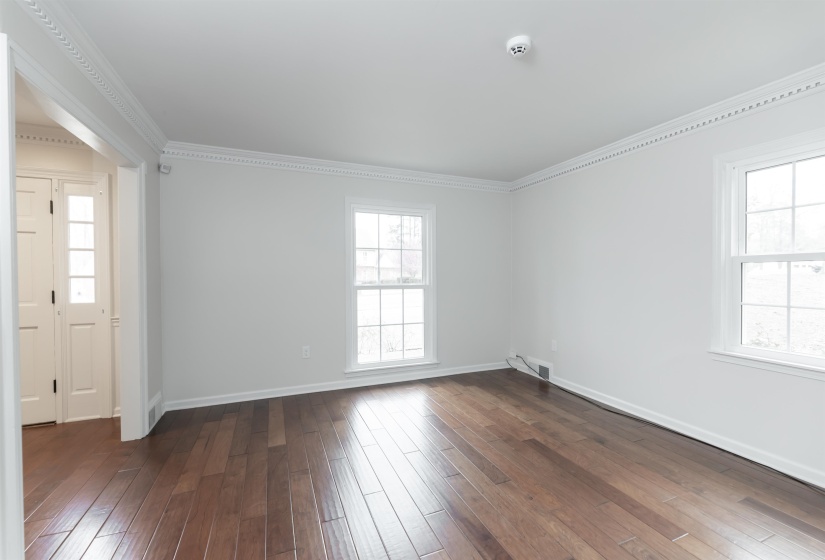 Empty room featuring crown molding, dark wood finished floors, and plenty of natural light