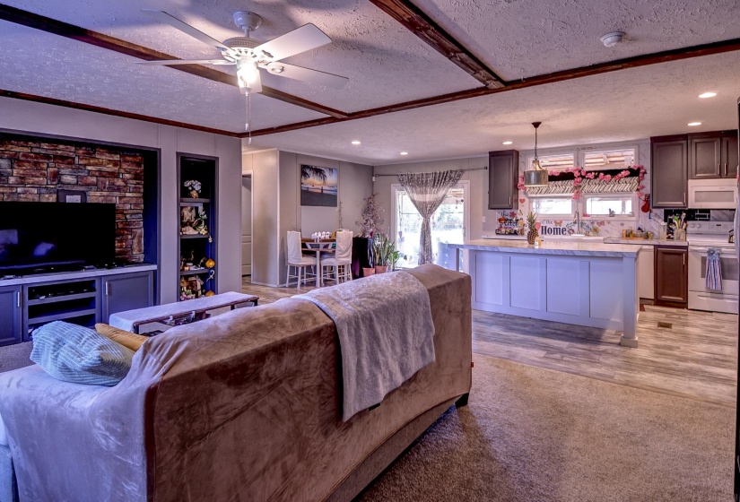 Living room featuring a textured ceiling, light colored carpet, and ceiling fan