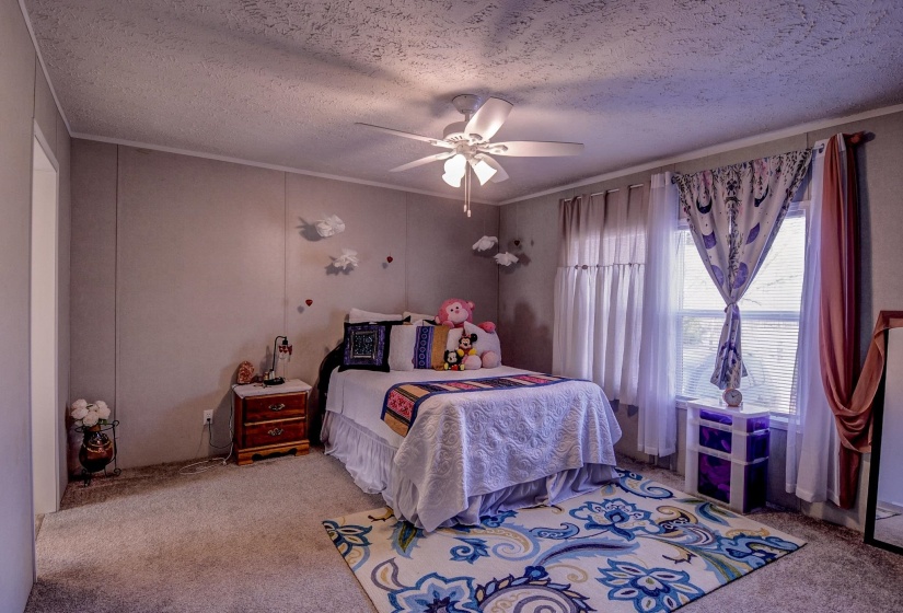 Bedroom with light carpet, a textured ceiling, and a ceiling fan