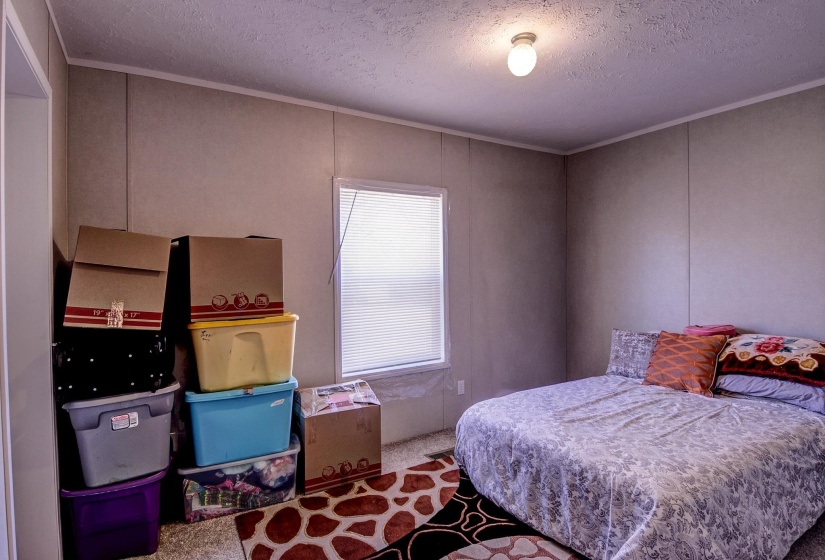 Bedroom with a textured ceiling, carpet floors, a decorative wall, and crown molding