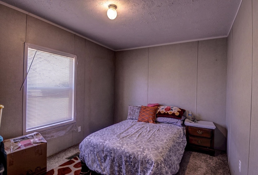 Bedroom featuring a textured ceiling, dark carpet, and a decorative wall