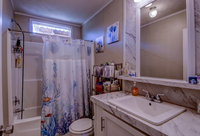 Full bathroom with a textured ceiling, vanity, shower / tub combo with curtain, and ornamental molding