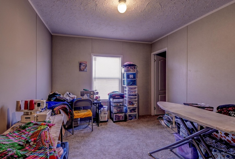 Carpeted bedroom featuring a decorative wall and a textured ceiling