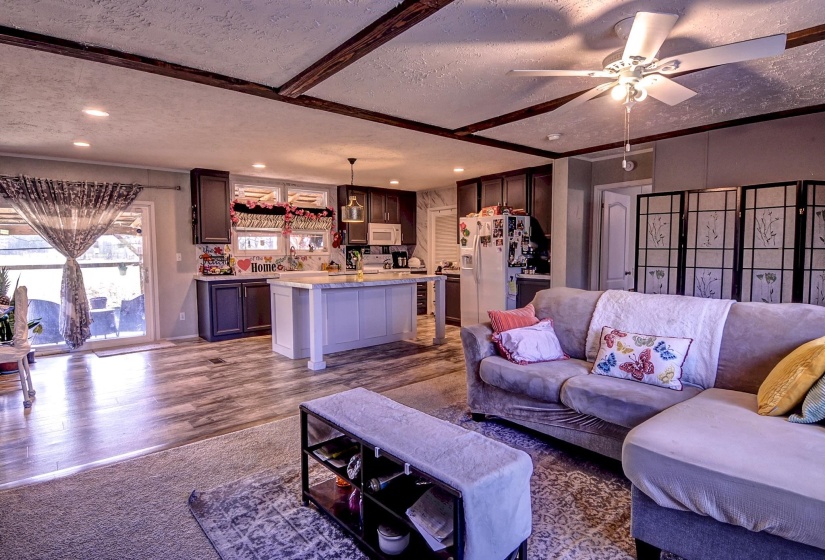 Living room with a textured ceiling, ceiling fan, and dark wood-style floors